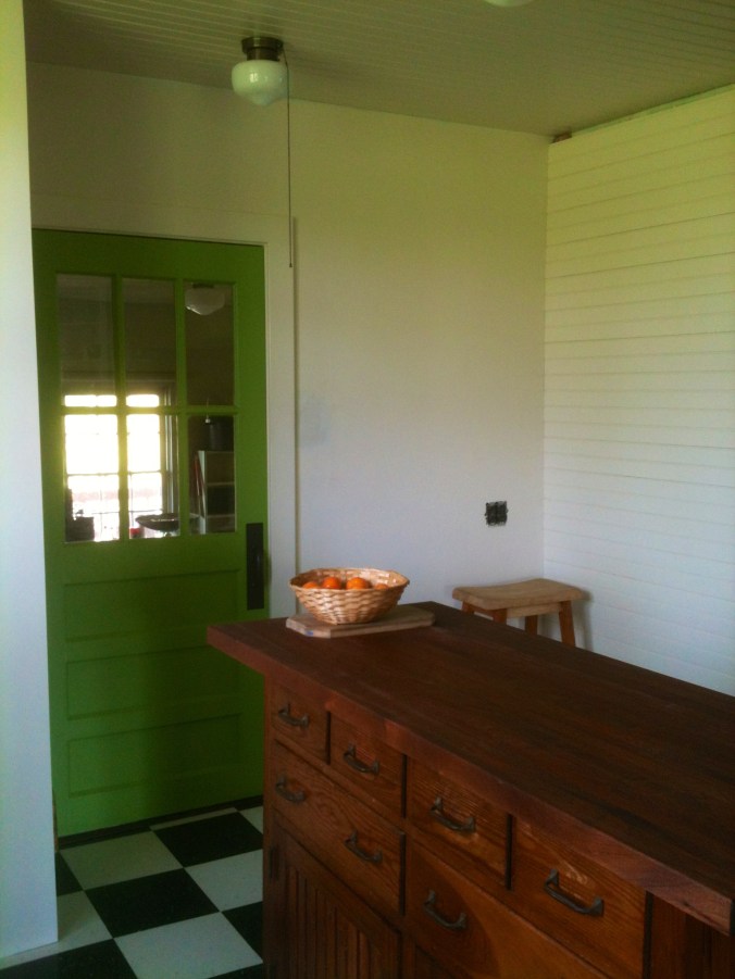 We've put the island back in place. A dark oak cupboard will go on the wall next to the green door.